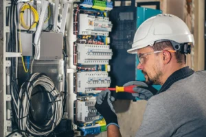 Man, an electrical technician working in a switchboard with fuses.