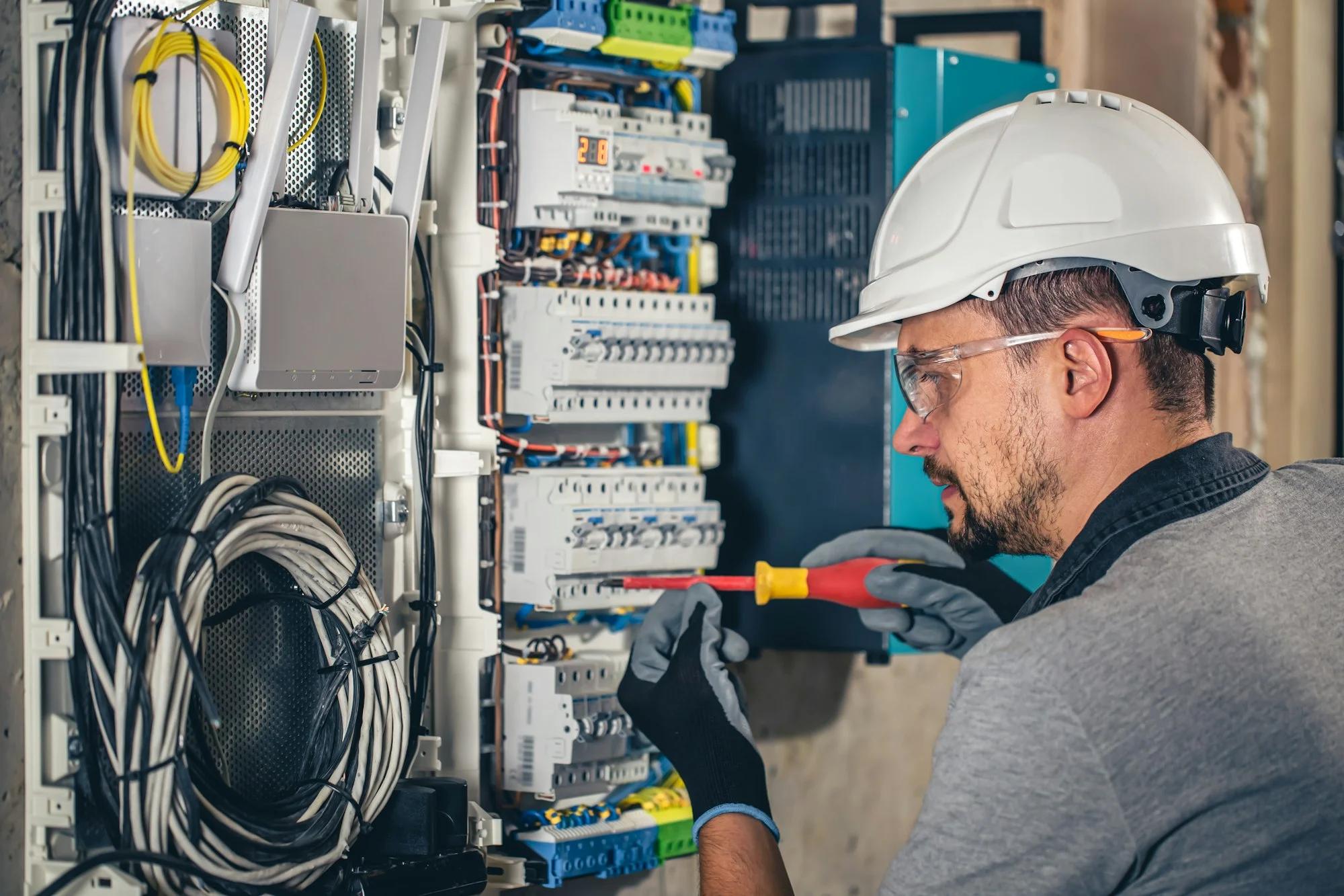 Man, an electrical technician working in a switchboard with fuses.